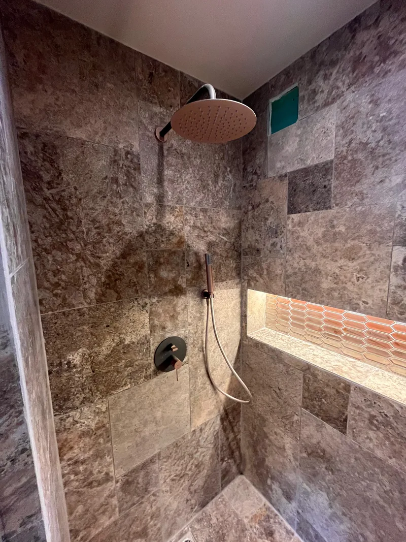 Douche &agrave; l&rsquo;italienne habill&eacute;e de dalles effet pierre, niche r&eacute;troéclair&eacute;e et pomme de t&ecirc;te, chantier SFG B&acirc;ti Concept