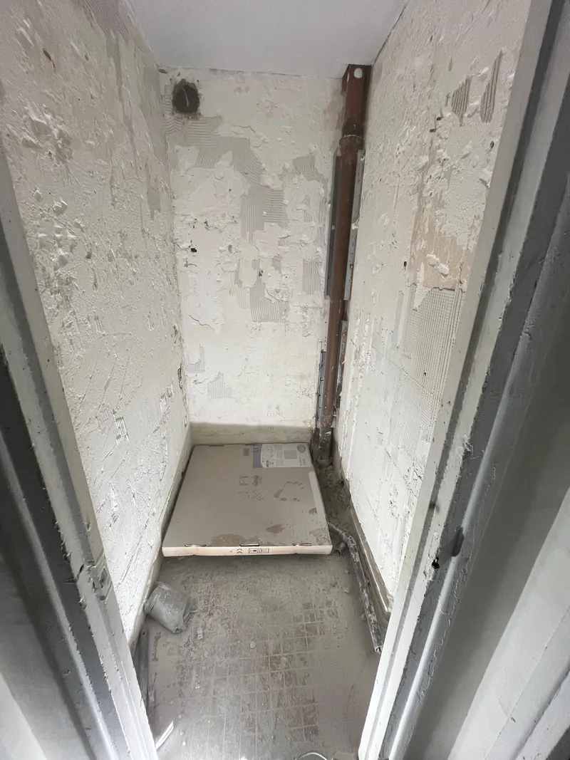 Salle d&rsquo;eau avant travaux, murs piqu&eacute;s et ancien receveur en place